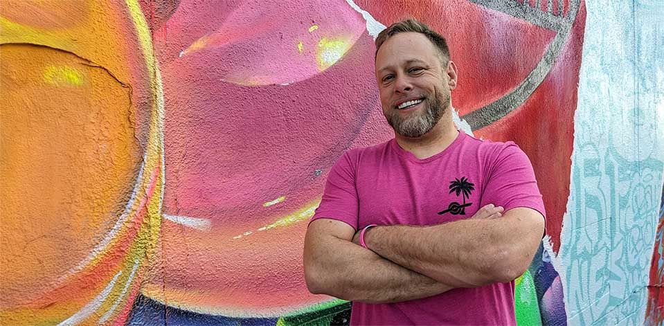 Cory Boehne standing in front of a colorful mural in Miami